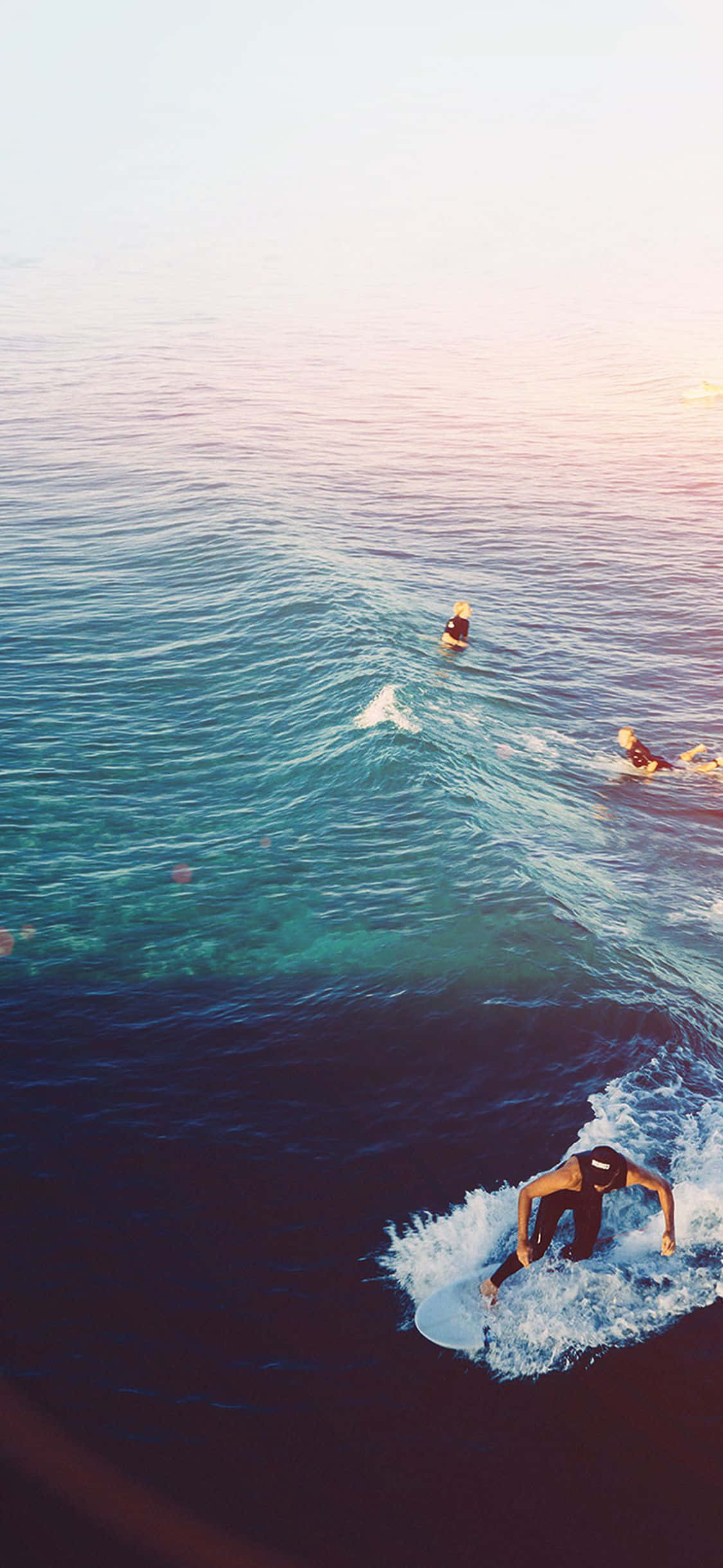 a group of people riding a wave in the ocean Picha ya Ukuta