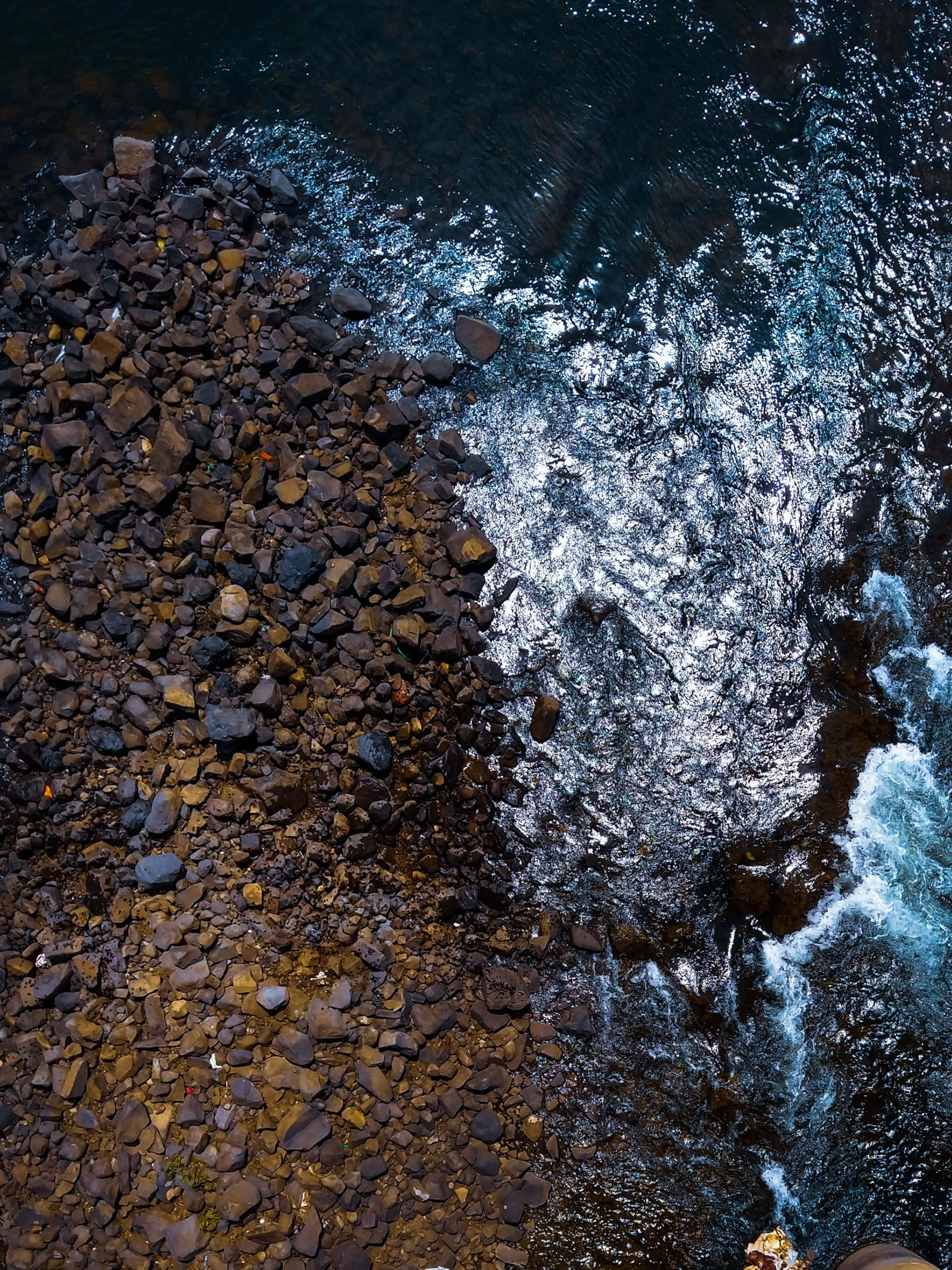 a man is standing on a cliff overlooking the water Picha ya Ukuta