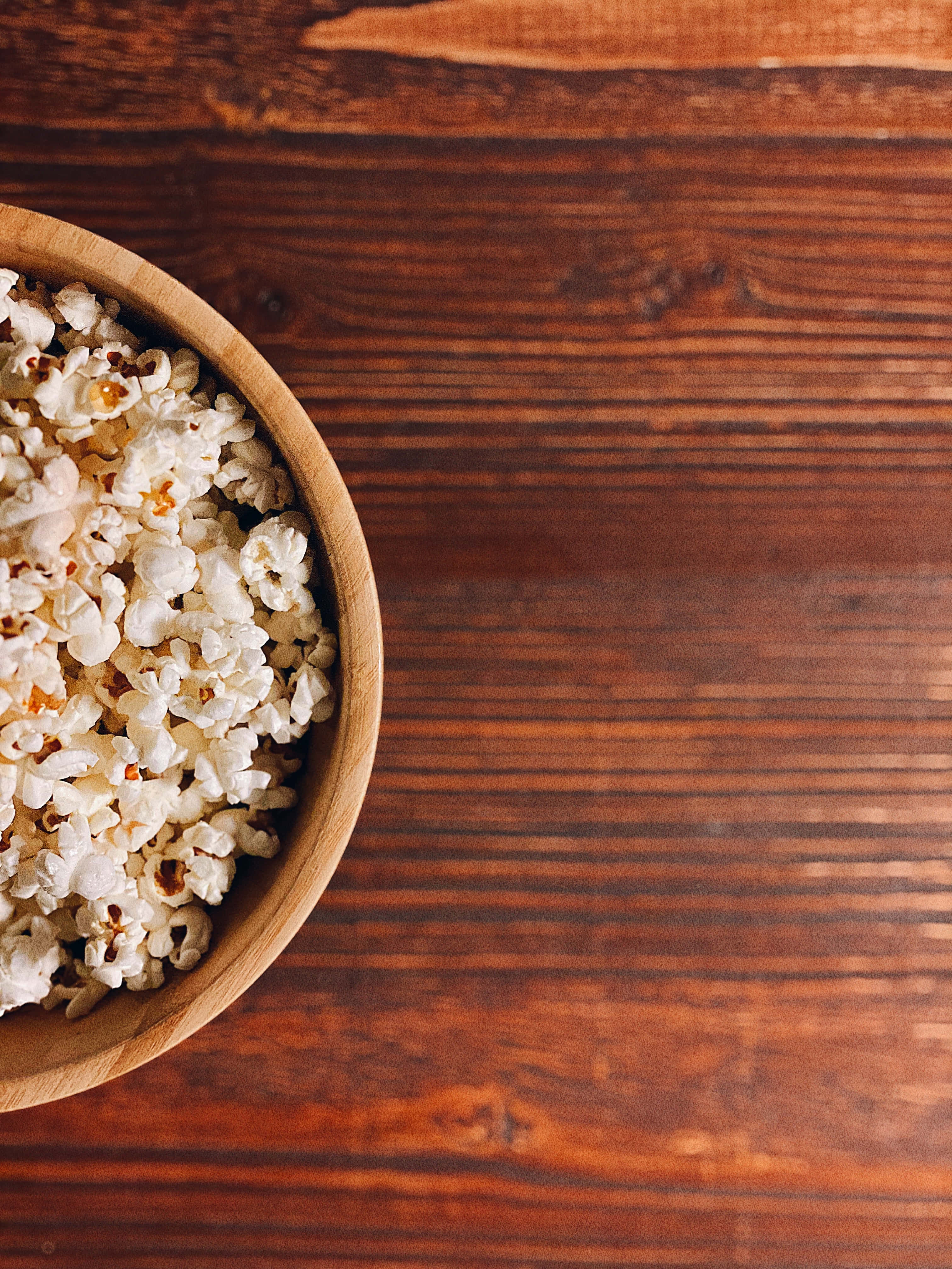 bakuli la popcorn kwenye meza ya mbao Picha ya Ukuta