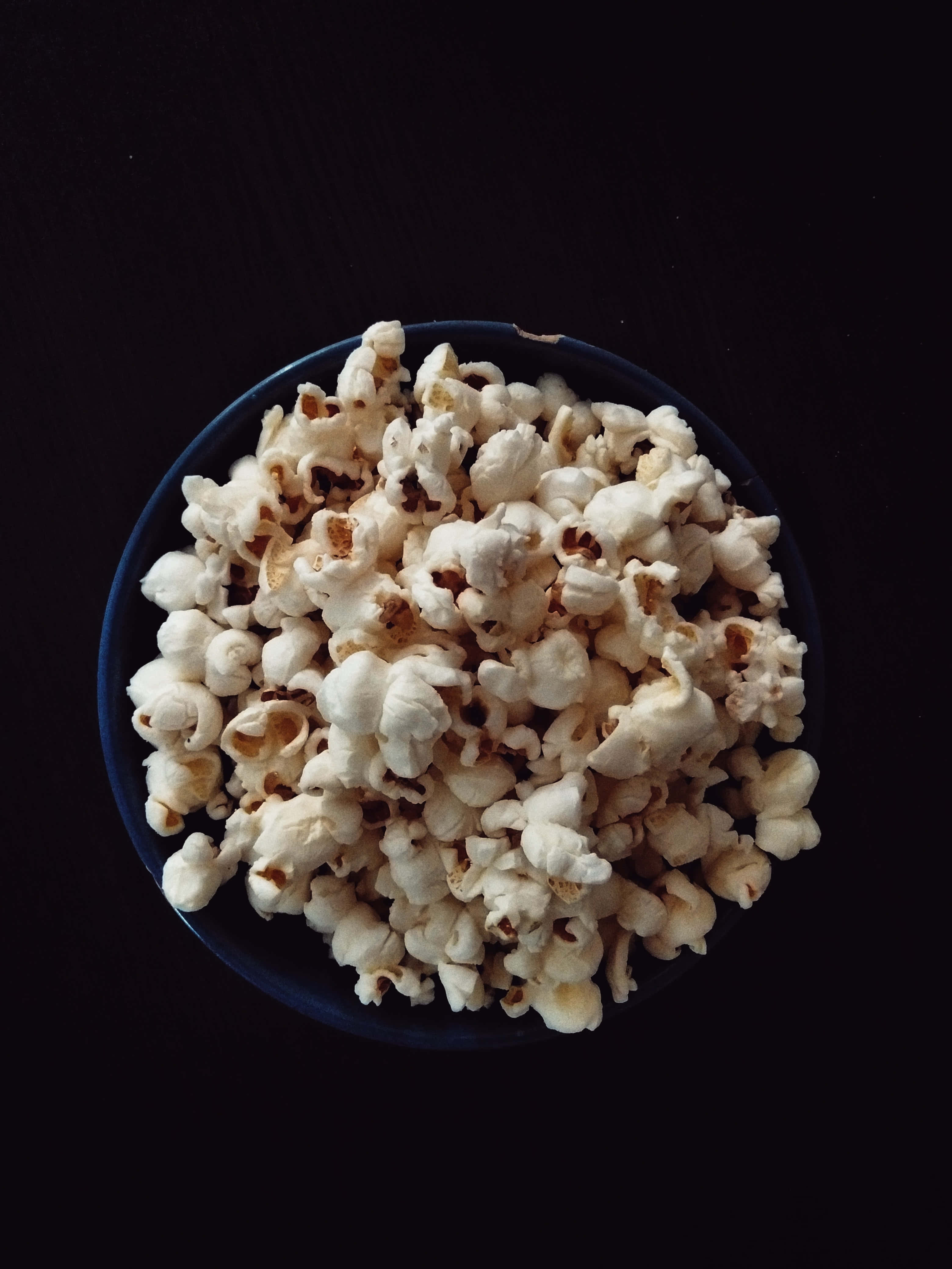 bakuli la popcorn kwenye meza nyeusi Picha ya Ukuta