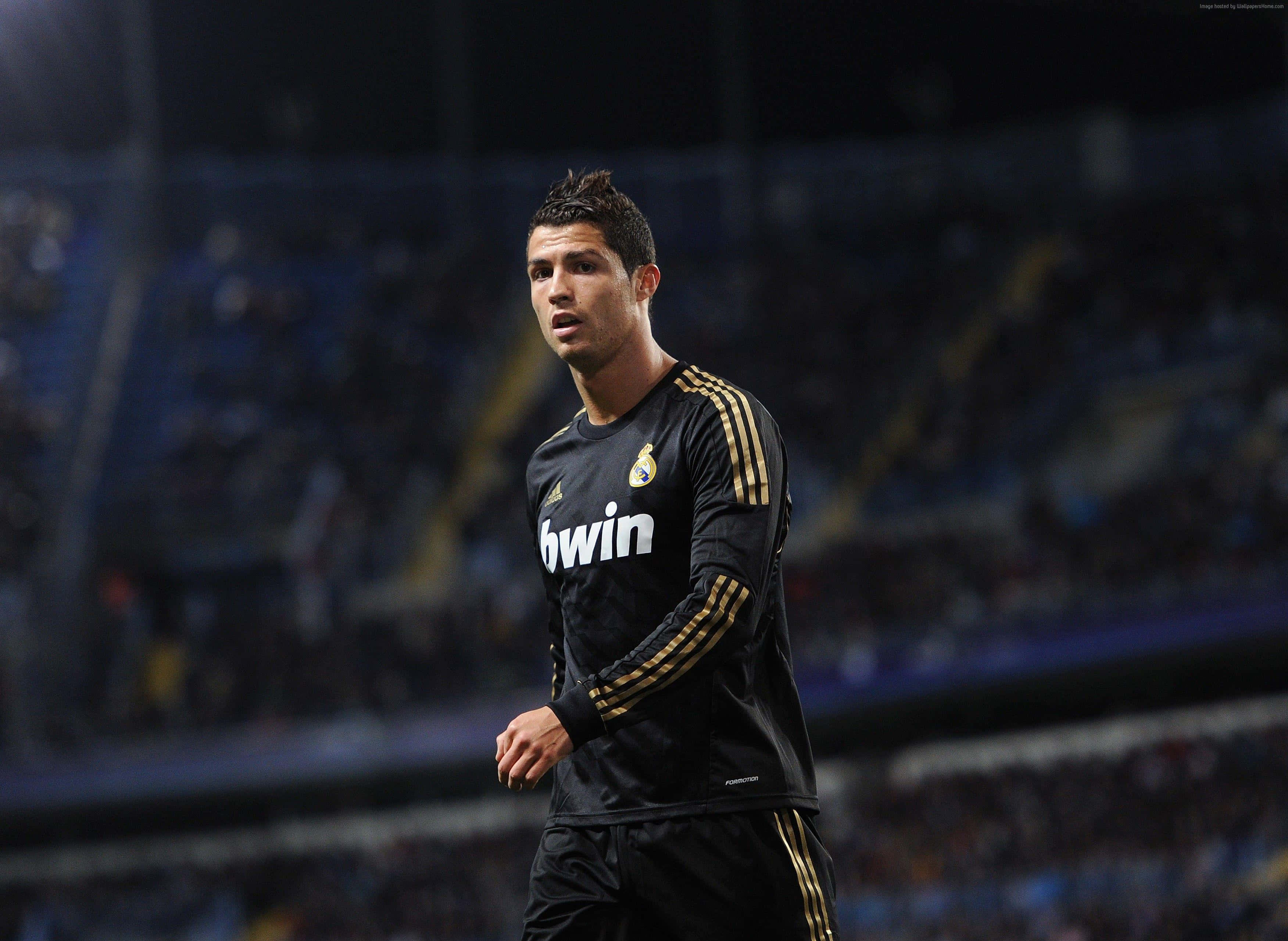 Cristiano Ronaldo akibeba mpira uwanjani wakati wa mechi ya soka Picha ya Ukuta