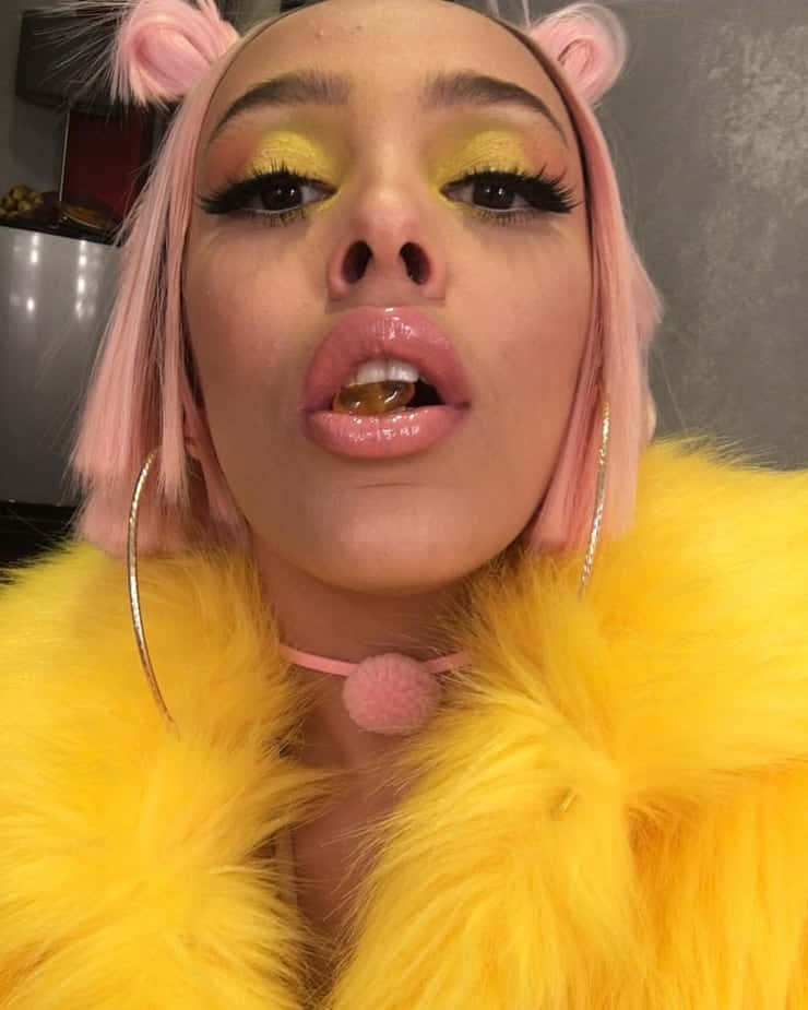 Doja Cat akiwa na mtindo wa kuvutia katika koti la manyoya la bluu la kustaajabisha. Picha ya Ukuta