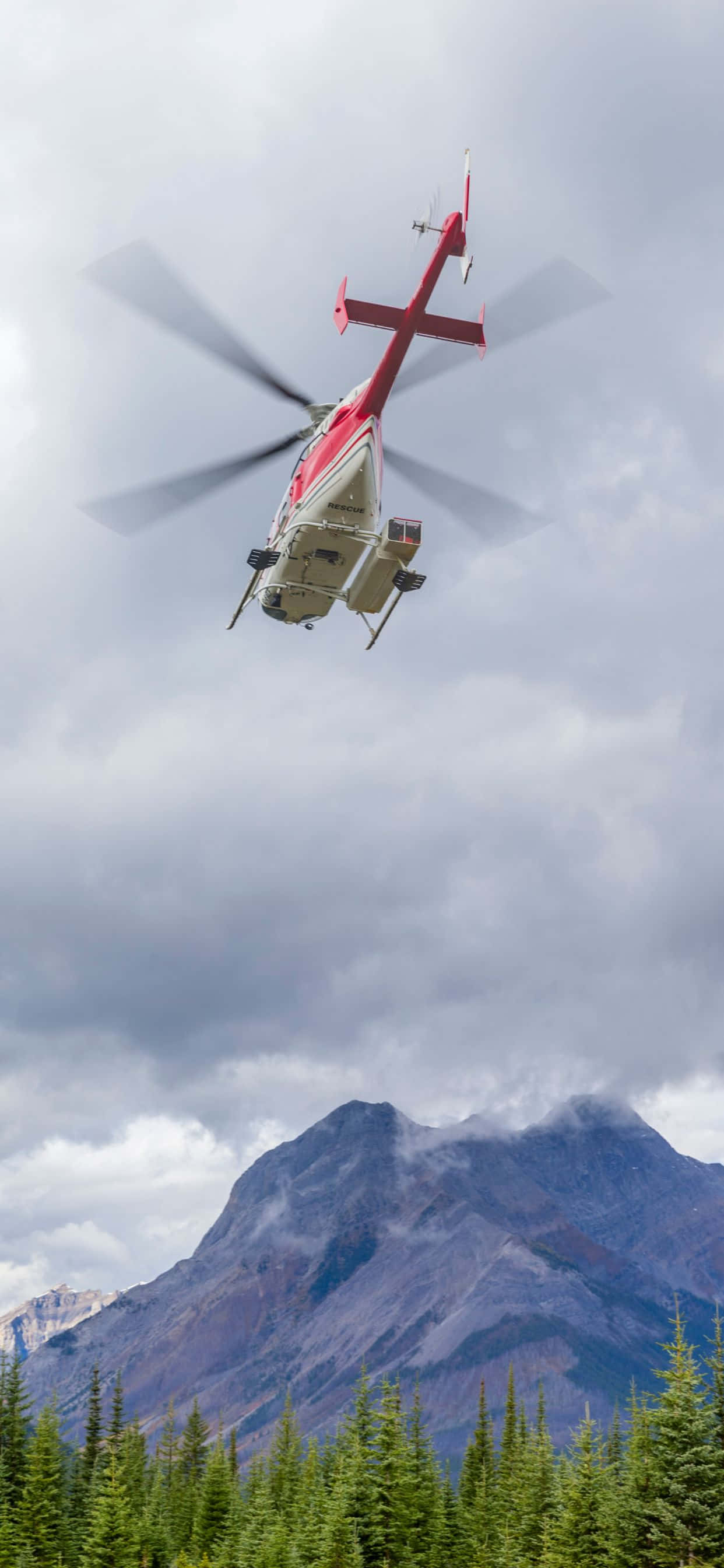 helikopta inayofanya safari juu ya msitu na milima nyuma Picha ya Ukuta