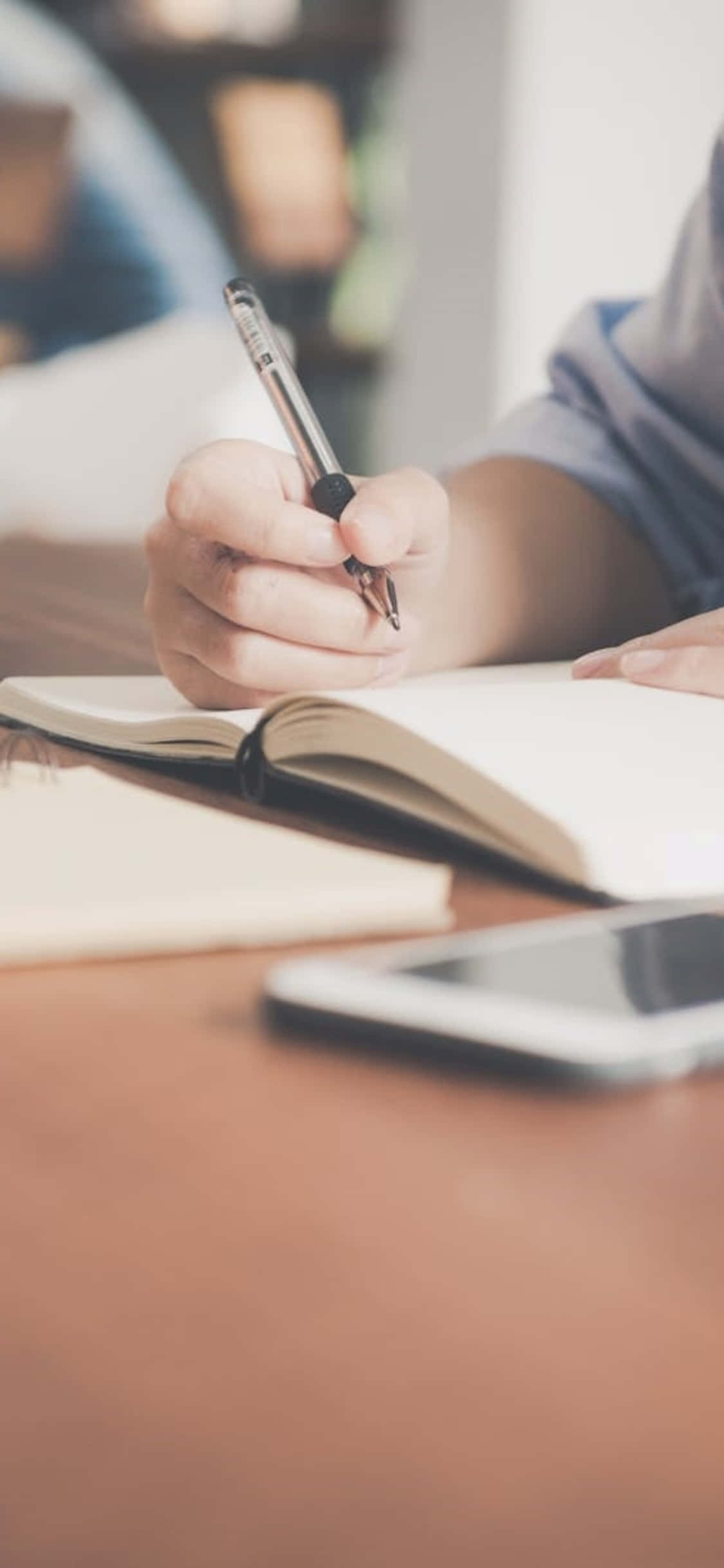 iPhone X Desk Background Person Writing On A Notebook Picha ya Ukuta