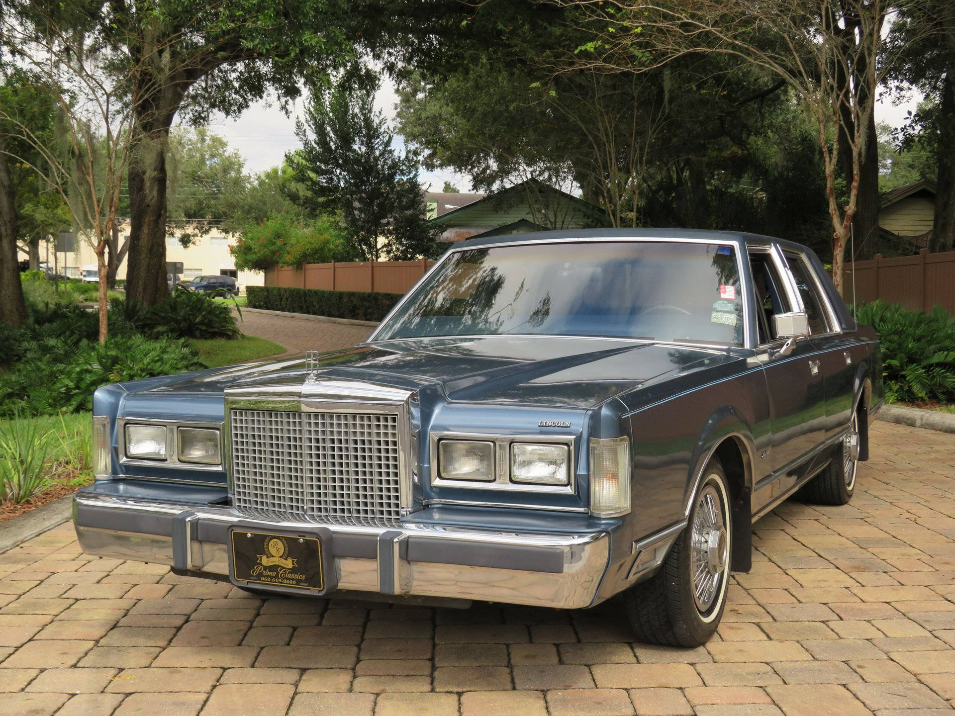 Majestic 1986 Lincoln Town Car iliyopakiwa kwenye Barabara ya Asfalt Picha ya Ukuta