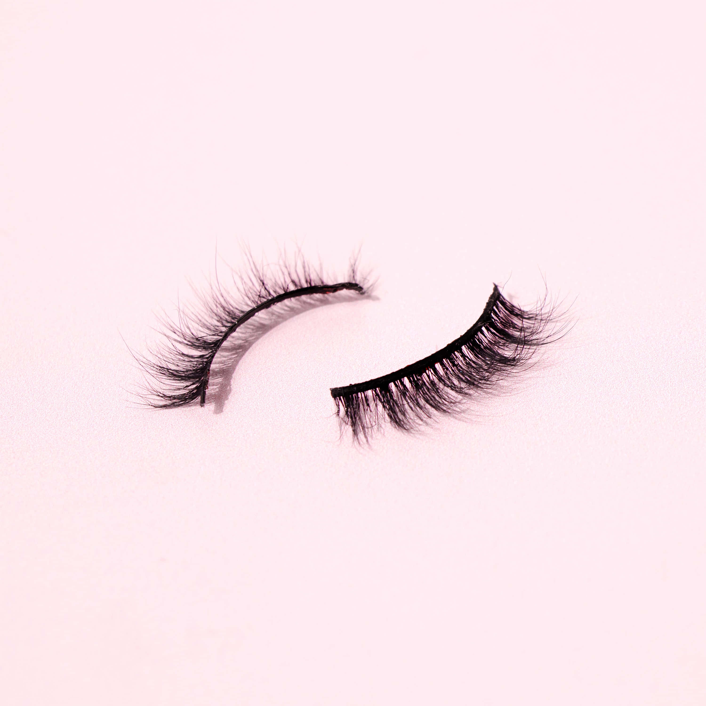 mbili za eyelashes za uongo kwenye nyuma ya pink Picha ya Ukuta