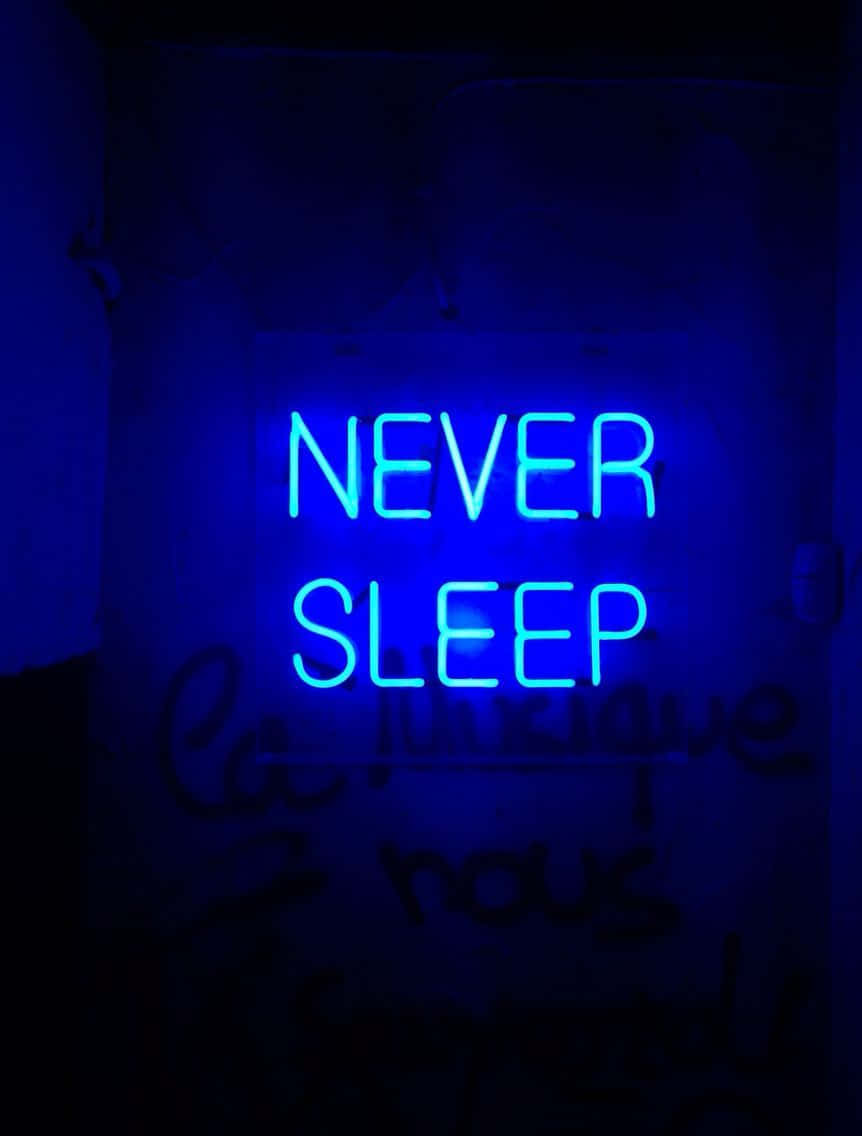 Mbingu ya usiku yenye mwanga wa neon inaangaza mji. Picha ya Ukuta