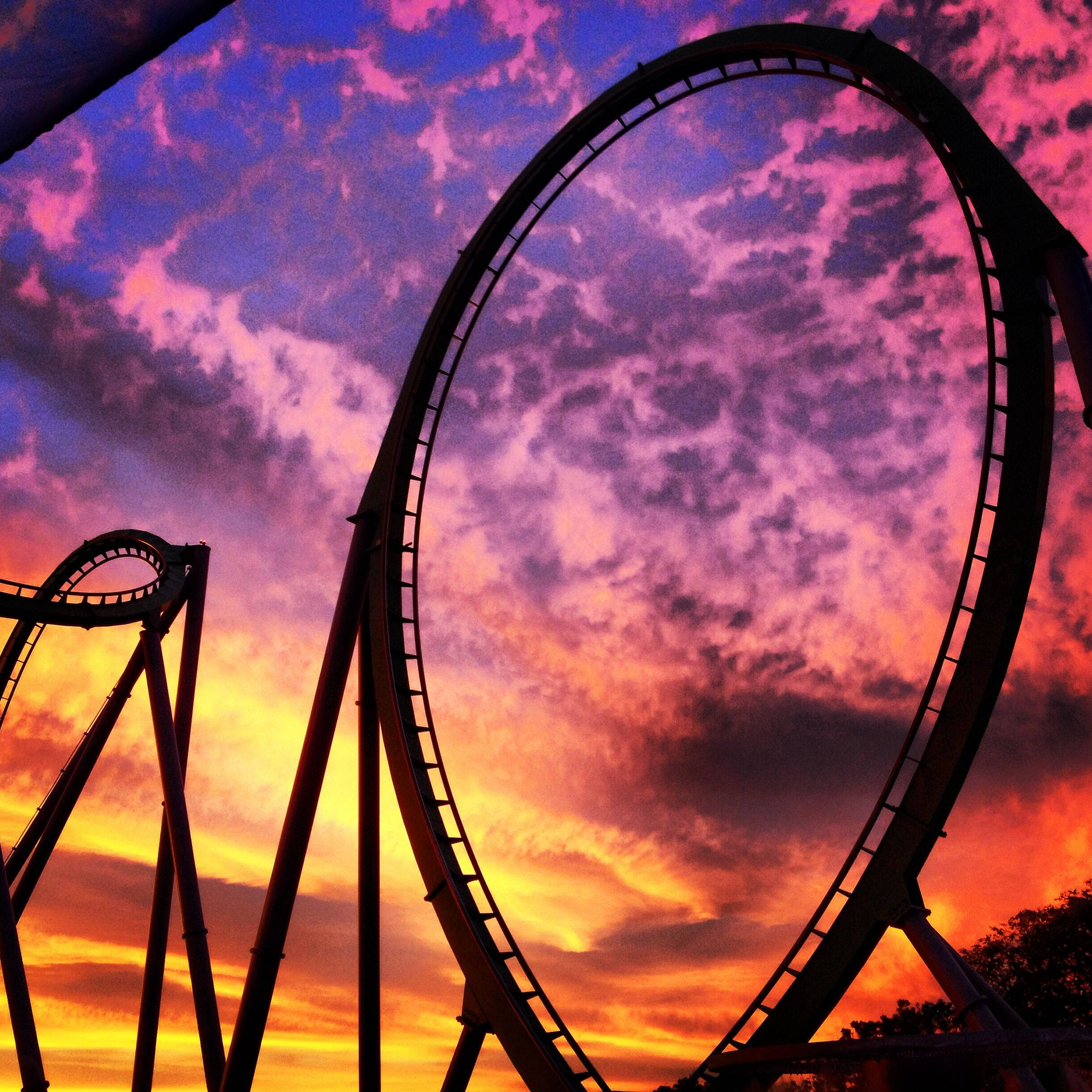Mafanikio ya Juu ya Roller Coaster katika Mwanga wa Sera ya Rangi ya Violet na Orange Picha ya Ukuta