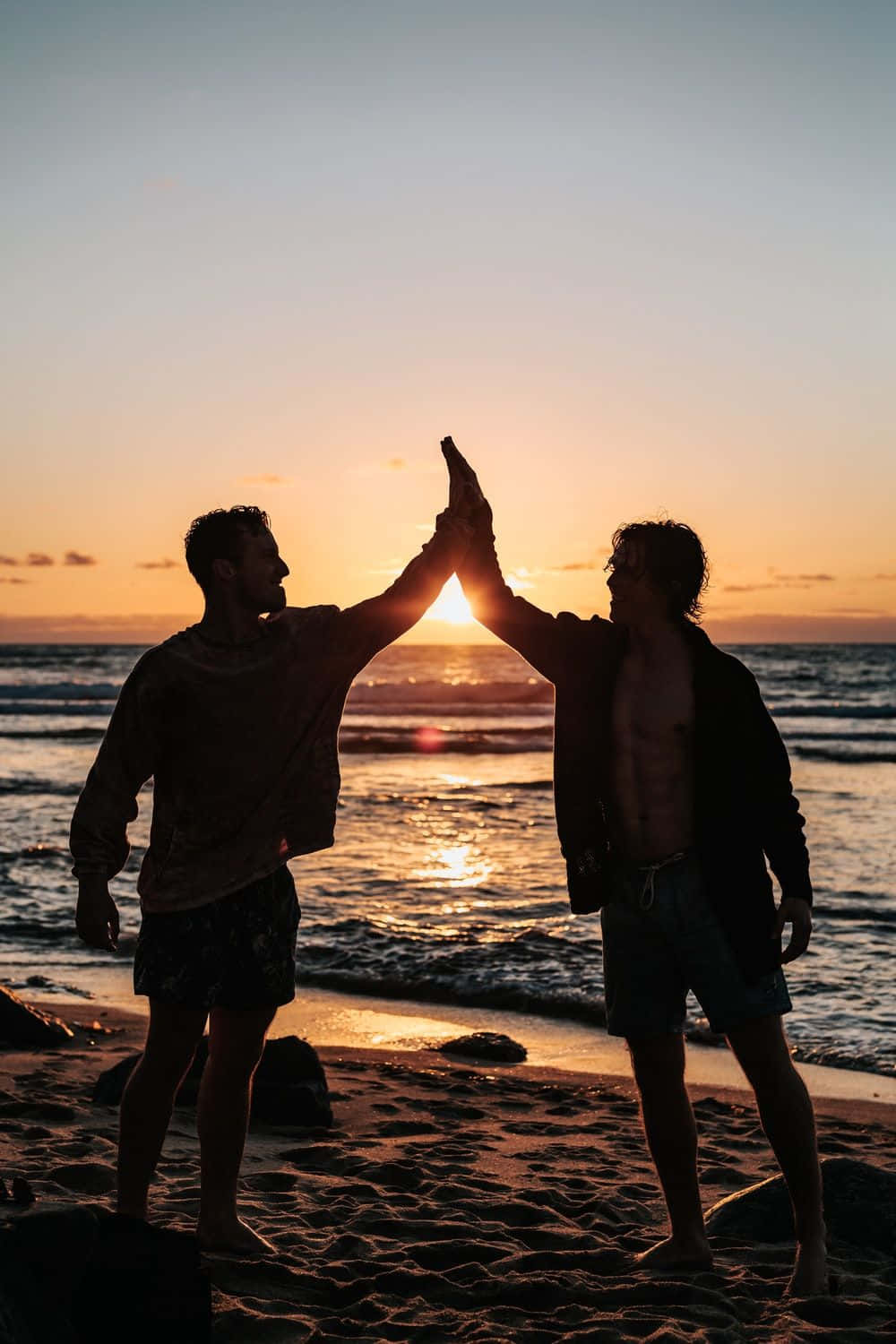 Picha ya Urafiki wa High Five Ufukweni Wakati wa Machweo Picha ya Ukuta