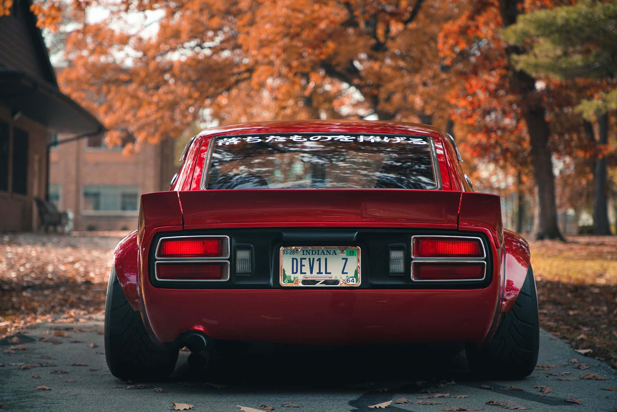Sleek red Datsun car parked on a city street Picha ya Ukuta
