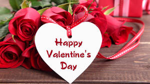 Bouquet of red roses lying on the table with a white heart card saying "Happy Valentine's Day". — Chromebook Picha ya Ukuta