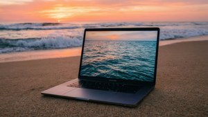 MacBook ya kupendeza kwenye pwani wakati wa mchana na sauti za bahari.