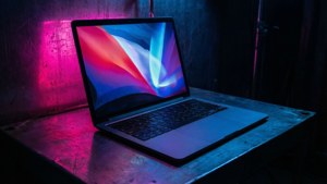 MacBook iliyochochewa na cyberpunk yenye mwanga wa neon katika chumba cha giza.