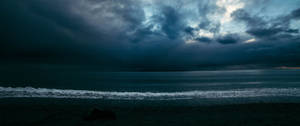 Ultrawide dark sky with some light showing on the ocean.