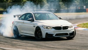 BMW M4 nyeupe inakwepa kwenye kona ya wimbo wa magari na moshi wa tairi na mwonekano wa mwendo — Bmw Picha ya Ukuta