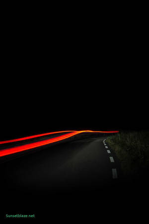 AMOLED wallpaper of an orange light trailing the road.