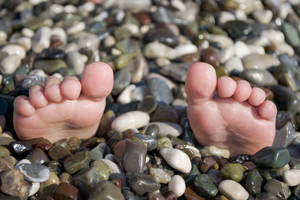 Feet on the rocks during Summer vacation, Funny situation on beach with pebbles.